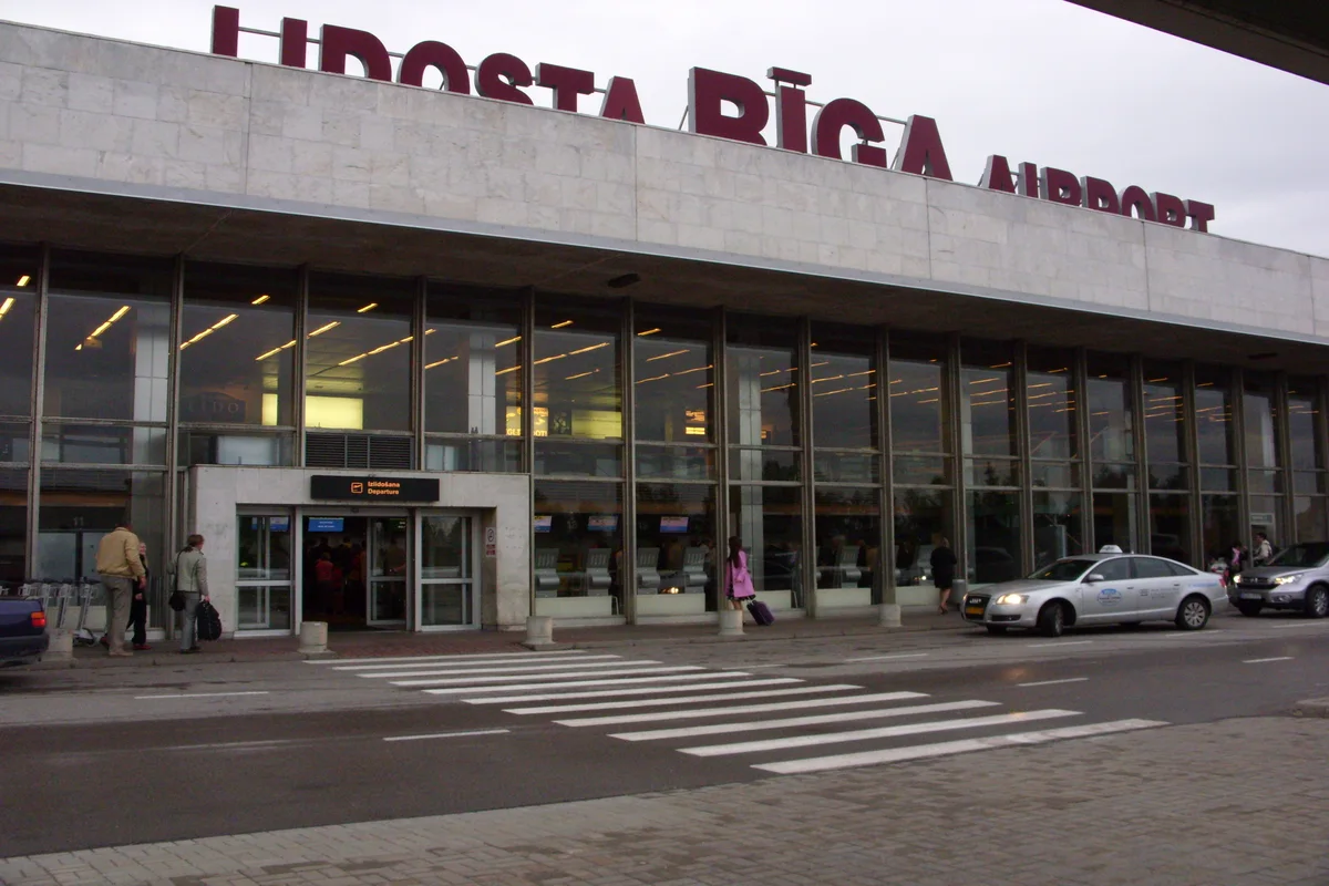 Reisende in einem Flughafenterminal unter einer Anzeigetafel mit Gate-Hinweisen