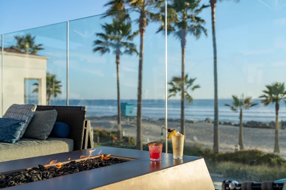 Feuerstelle und zwei Drinks auf dem Sun Deck des Hotel del Coronado mit Blick auf Strand und Palmen
