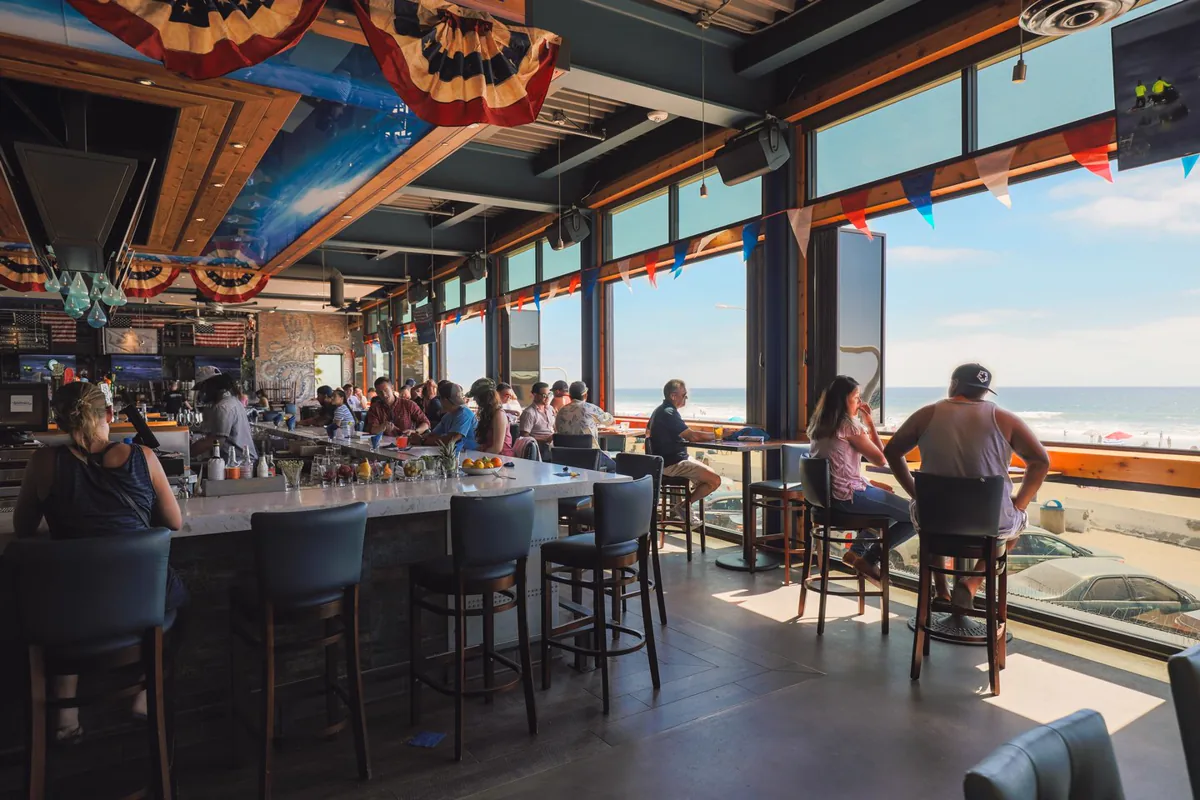 Gäste an der Bar der Waterbar mit Blick auf Strand und Pazifik in Pacific Beach