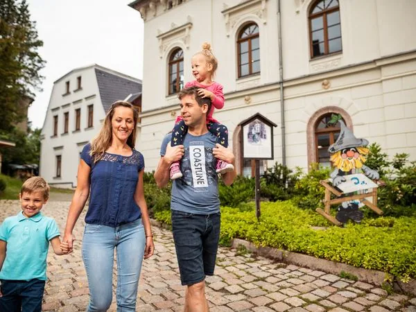 Familie spaziert in Eibenstock im Erzgebirge vor einem historischen Gebäude